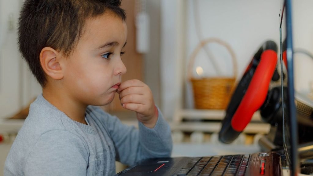 Education: Young child looking thoughtfully at a computer screen, illustrating the role of independent thinking and discernment as children increasingly interact with AI.