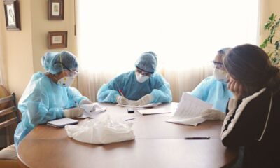 NMC: Medical professionals in protective equipment review documents during a patient safety meeting.