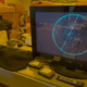 Computer monitor displaying cosmic-ray particle tracks in a physics laboratory.