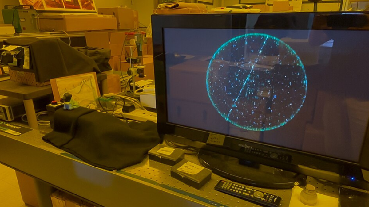 Computer monitor displaying cosmic-ray particle tracks in a physics laboratory.
