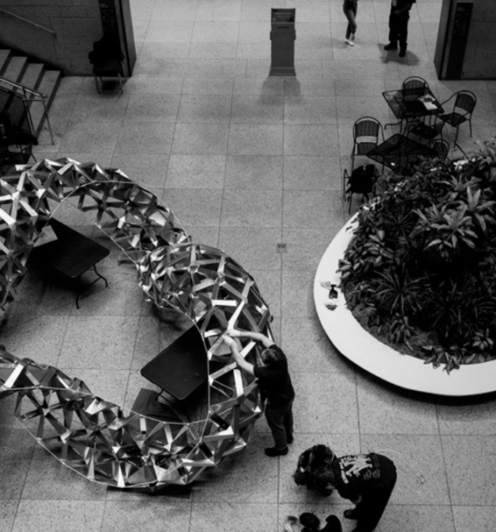 Folded aluminium geometric structure displayed in a public library atrium, demonstrating an origami-inspired architectural design.