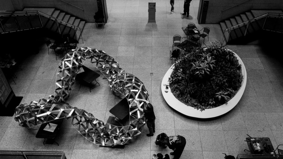 Folded aluminium geometric structure displayed in a public library atrium, demonstrating an origami-inspired architectural design.