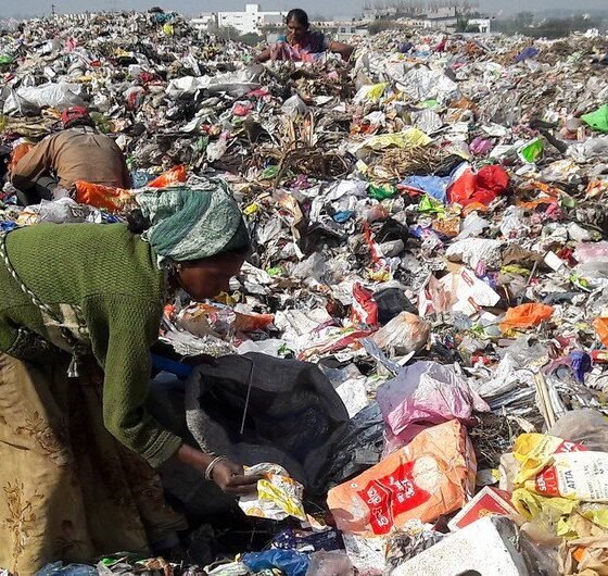 Waste pickers sorting through a large landfill filled with discarded plastic and other waste.