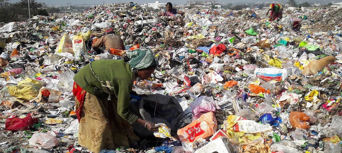 Waste pickers sorting through a large landfill filled with discarded plastic and other waste.