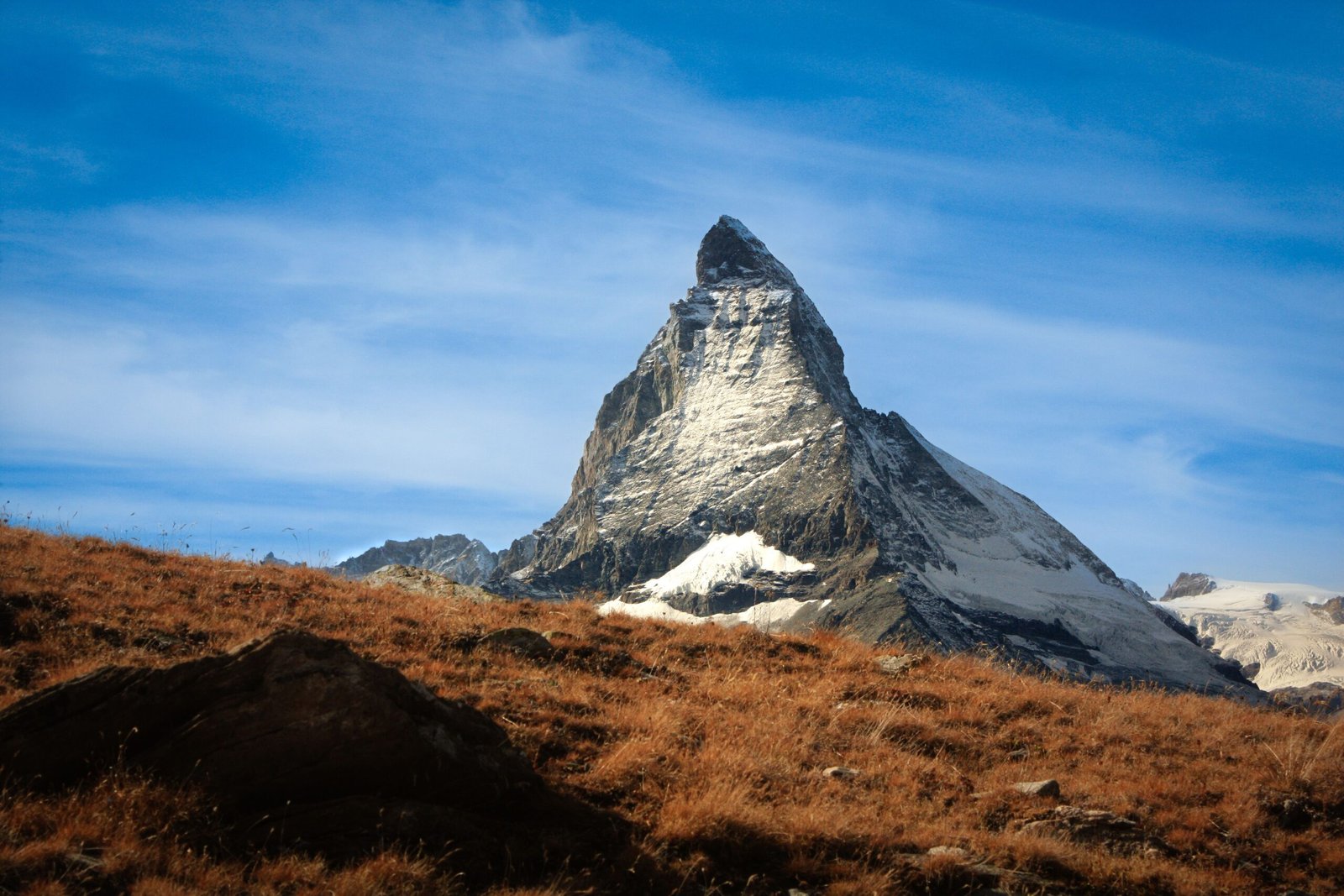 Matterhorn mountain with snow-covered slopes rising above a dry Alpine landscape in Switzerland