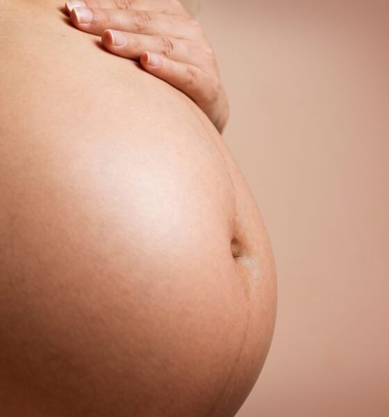 Close-up of a pregnant woman gently resting her hand on her abdomen.