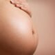 Close-up of a pregnant woman gently resting her hand on her abdomen.