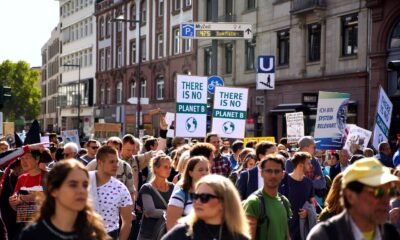 Climate protesters march through a city street holding “There Is No Planet B” placards during a climate change demonstration.
