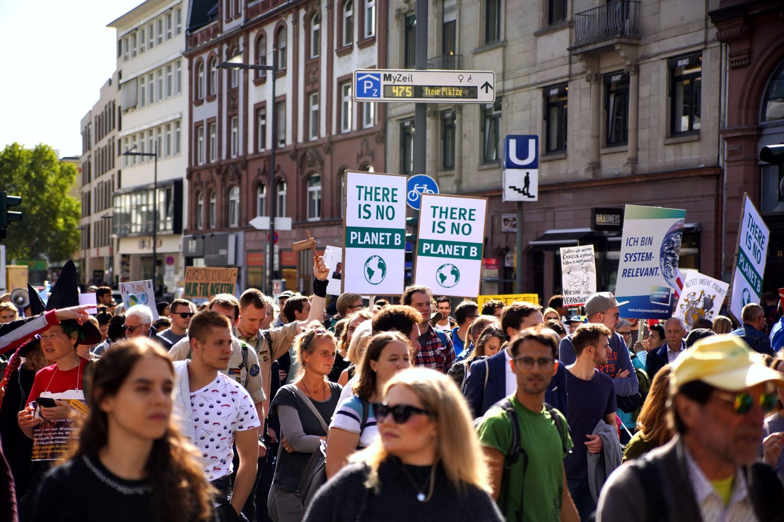 Climate protesters march through a city street holding “There Is No Planet B” placards during a climate change demonstration.