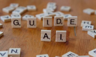 Wooden letter tiles spelling “GUIDE AI” on a table, representing AI governance and safety