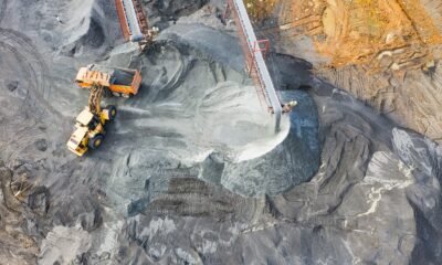 Open-pit coal mine with heavy machinery, conveyor belts and piles of extracted coal.