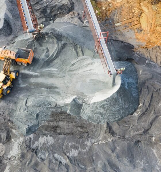 Open-pit coal mine with heavy machinery, conveyor belts and piles of extracted coal.