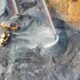Open-pit coal mine with heavy machinery, conveyor belts and piles of extracted coal.